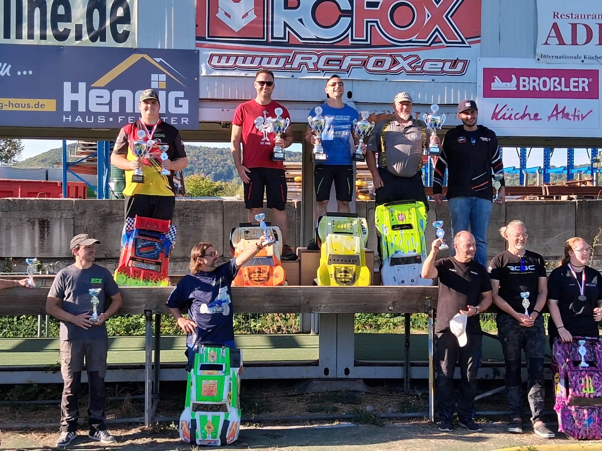 Siegerehrung der OR6-DM in Großheubach mit Fahrern, Pokalen und ihren RC-Fahrzeugen.